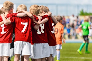 Boys Soccer Team. Children Football Academy. Kids Soccer Players in Red Shirts Standing Together on the Pitch. Youth Soccer Motivational Speech. Coach Motivational Talk With Young Boys